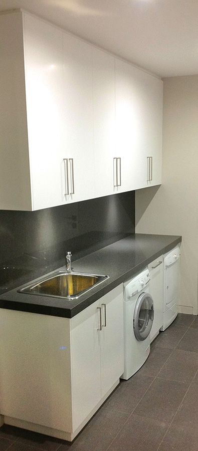White gloss laundry cabinetry with tall storage and integrated sink